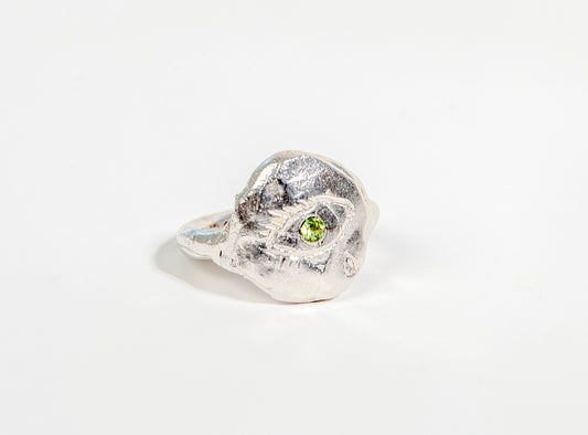 silver ring engraved with a crying eye. pupil is set with a peridot
