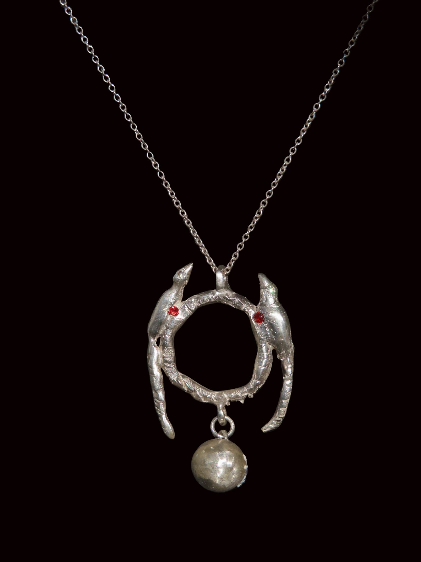 Silver necklace with a unique pendant on a black background